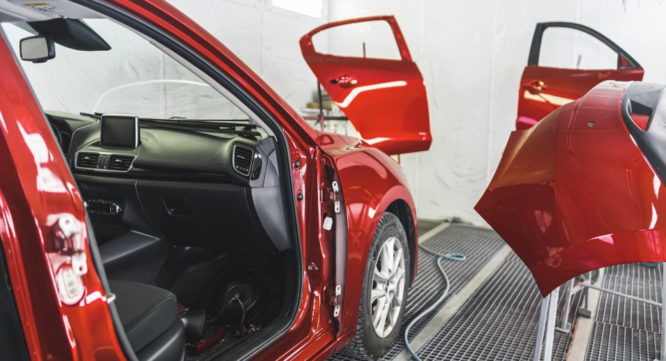 a red car that some is painting and replacing the car's door